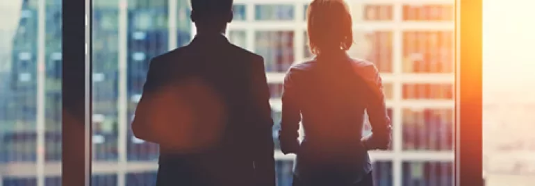 Silhouettes of two people looking out a window at a cityscape.