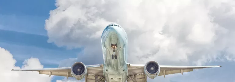 Airplane flying high against a backdrop of fluffy clouds.