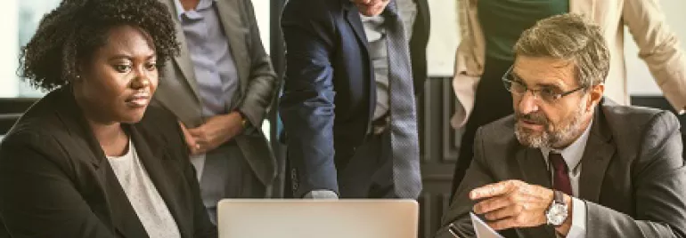Group of people having a meeting around a laptop in an office.