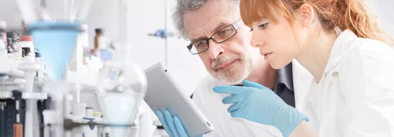 Researchers in a lab examining a tablet.