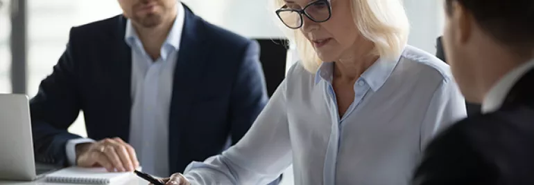 People in a meeting discussing documents at a conference table.