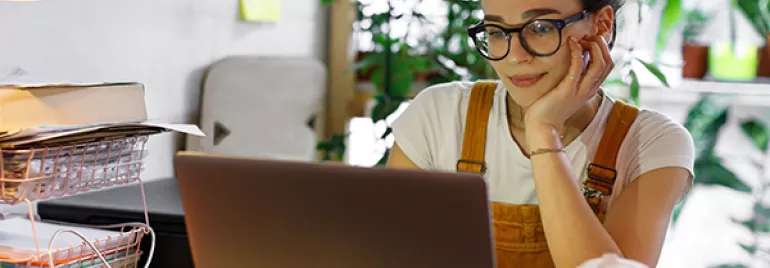 Person working on a laptop in a cozy room with plants.