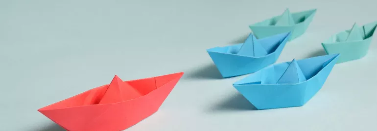 Colorful paper boats on a light blue background.