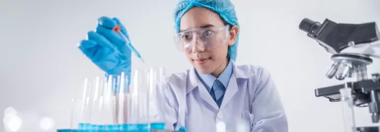 Scientist wearing protective gear working with test tubes in a laboratory.