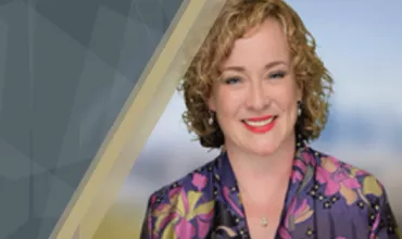 Person smiling, wearing a floral jacket with a geometric background.