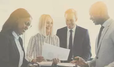 Group of professionals discussing a document in a bright office.