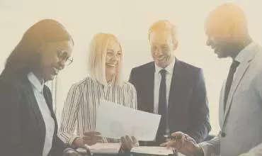Group of professionals discussing a document in a bright office.