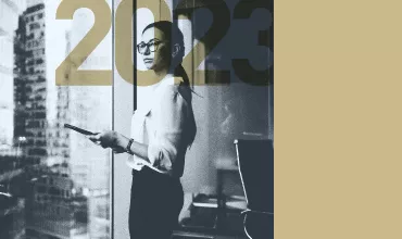 Person with glasses holding a tablet in a modern office with 2023 overlay.
