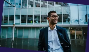 Person in business attire standing outside a modern glass office building.