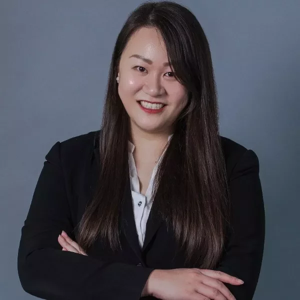 Person in business attire smiling with arms crossed
