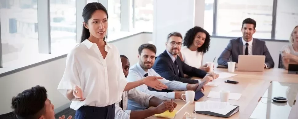 Person leading a meeting with a diverse team around a conference table.