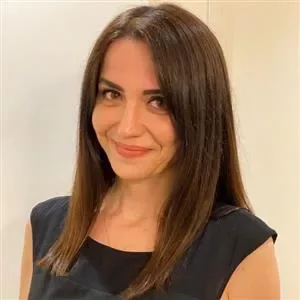 Person smiling with straight, dark hair against a plain background.