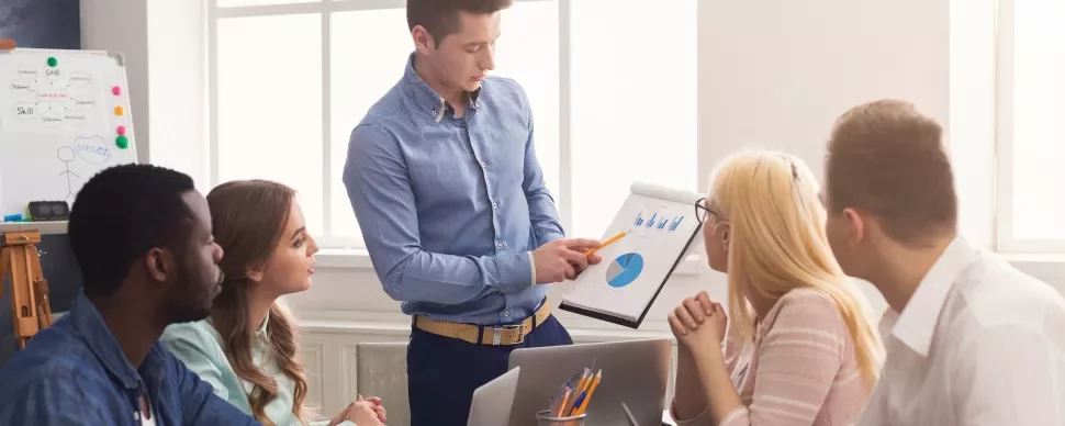 Team meeting with a presentation on charts and graphs displayed on a notepad.