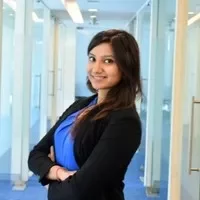 Person smiling in a hallway with glass doors.