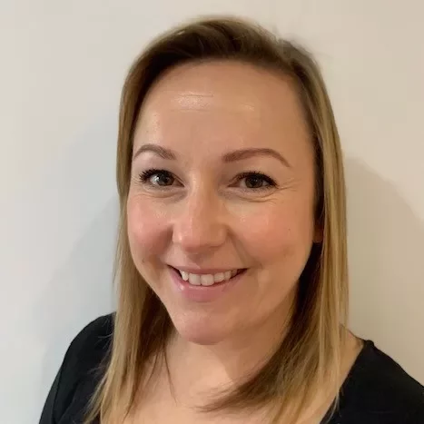 Person smiling against a plain background.