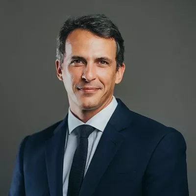 Person in a suit posing against a neutral background.