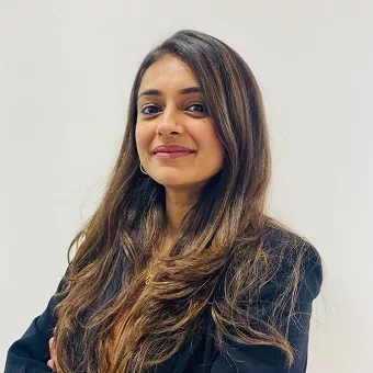 Person smiling, wearing a black jacket, with long brown hair against a white background.
