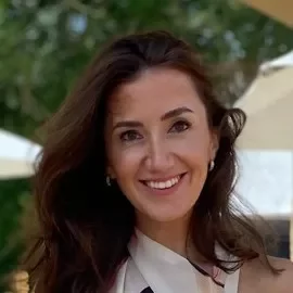 Person smiling outdoors with trees in background