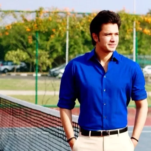 Person in blue shirt standing by a tennis court.