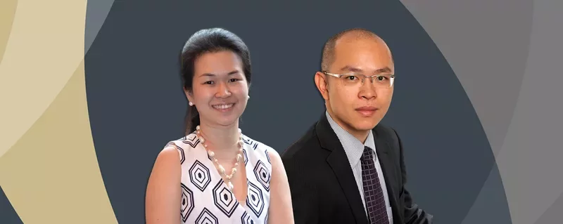 Two individuals smile in front of a geometric backdrop.