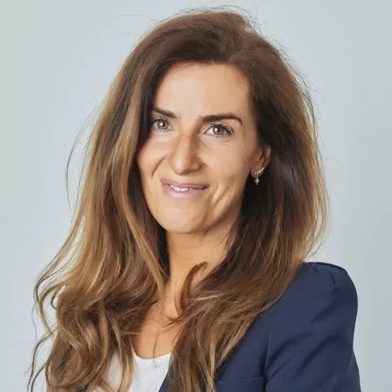 Portrait of a smiling person with long brown hair wearing a blue blazer.