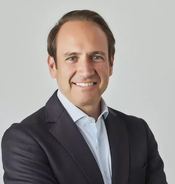 Person in a suit smiling with arms crossed.