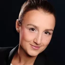 Person smiling in a professional headshot with dark background.