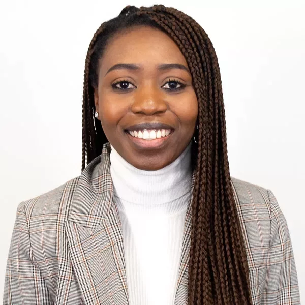 Person smiling in plaid blazer and white turtleneck.
