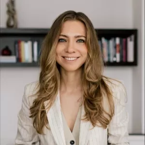 Person smiling in an office setting, wearing a striped blazer.