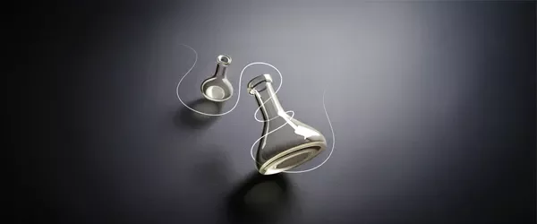 Two laboratory flasks on a dark surface; one lying on its side and the other standing upright.