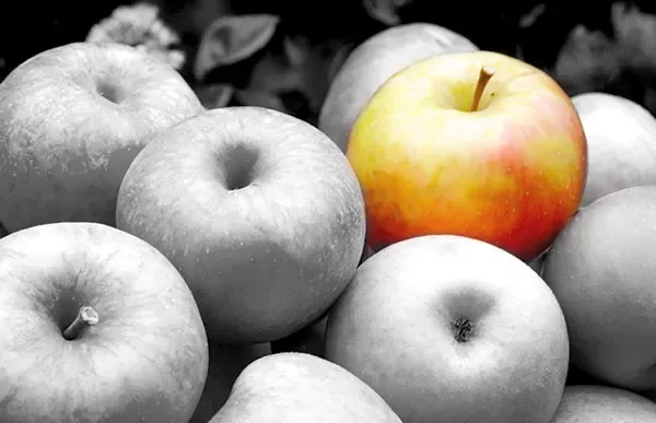 A single colored apple among grayscale apples.