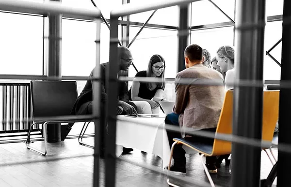 Group of people sitting around a table in a modern office space.
