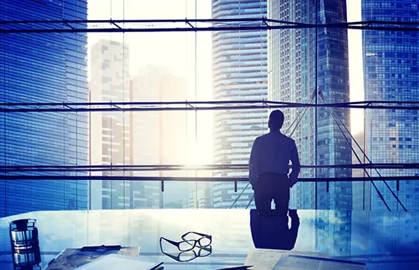 Person looking out at city skyline through large office window.