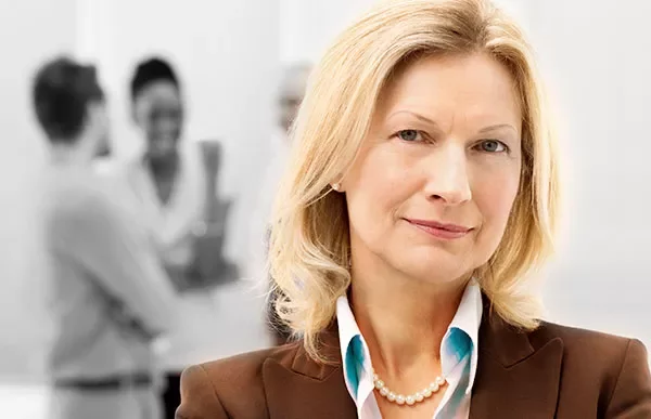 Person smiling with blurred group in the background.