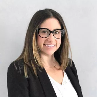 Person wearing glasses with shoulder-length hair and a blazer.