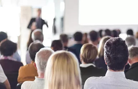 Audience attending a presentation in a bright room.