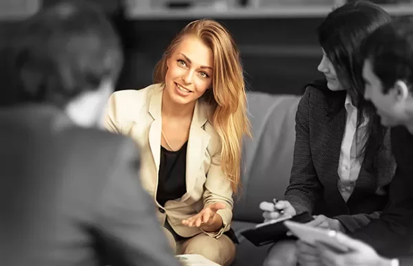 Person in a suit leading a group discussion, seated in a professional setting.