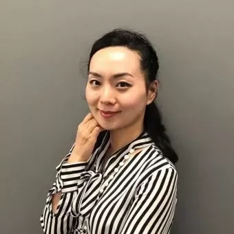 Person in striped shirt smiling against gray background.