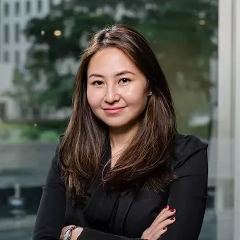 Person smiling in an office setting with arms crossed.