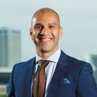 Person in a suit smiling against a city backdrop.
