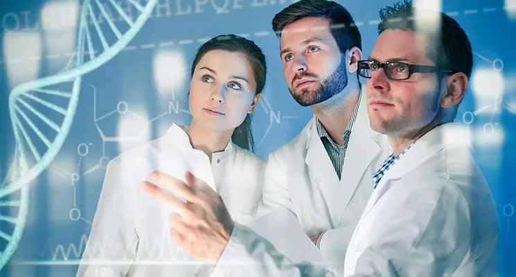 Three people in lab coats study digital DNA graphics.