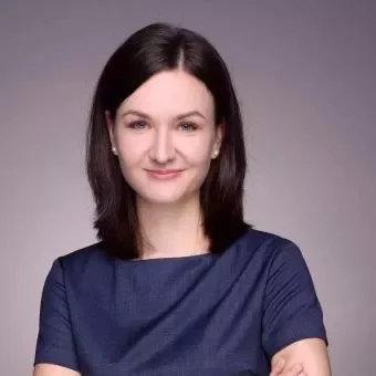 Person smiling with dark hair and blue top against gray background.