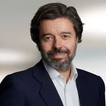 Person with a beard wearing a suit and white shirt, smiling at the camera.