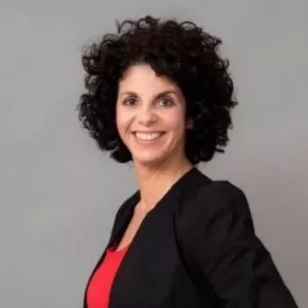 Person with curly hair smiling, wearing a black jacket over a red top.