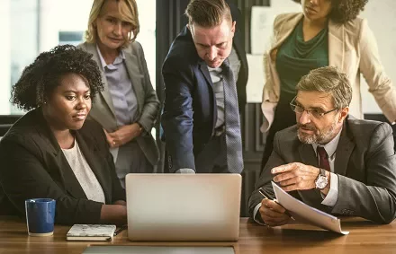 Group of people having a meeting around a laptop in an office.
