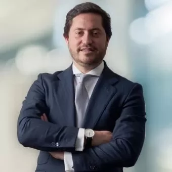 Person in a blue suit with arms crossed, smiling at the camera.