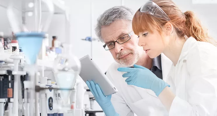 Researchers in a lab examining a tablet.