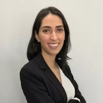 Person smiling in a professional outfit against a plain background.