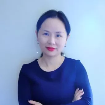 Person with crossed arms, wearing a dark blue top, standing against a light background.