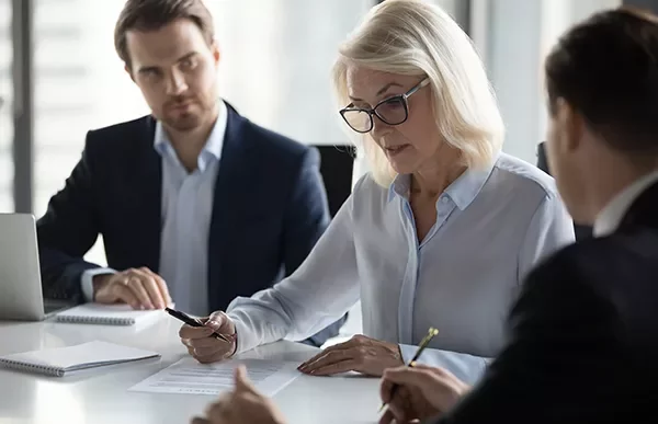 People in a meeting discussing documents at a conference table.